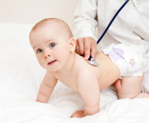 доктор слушает младенца стетоскопом